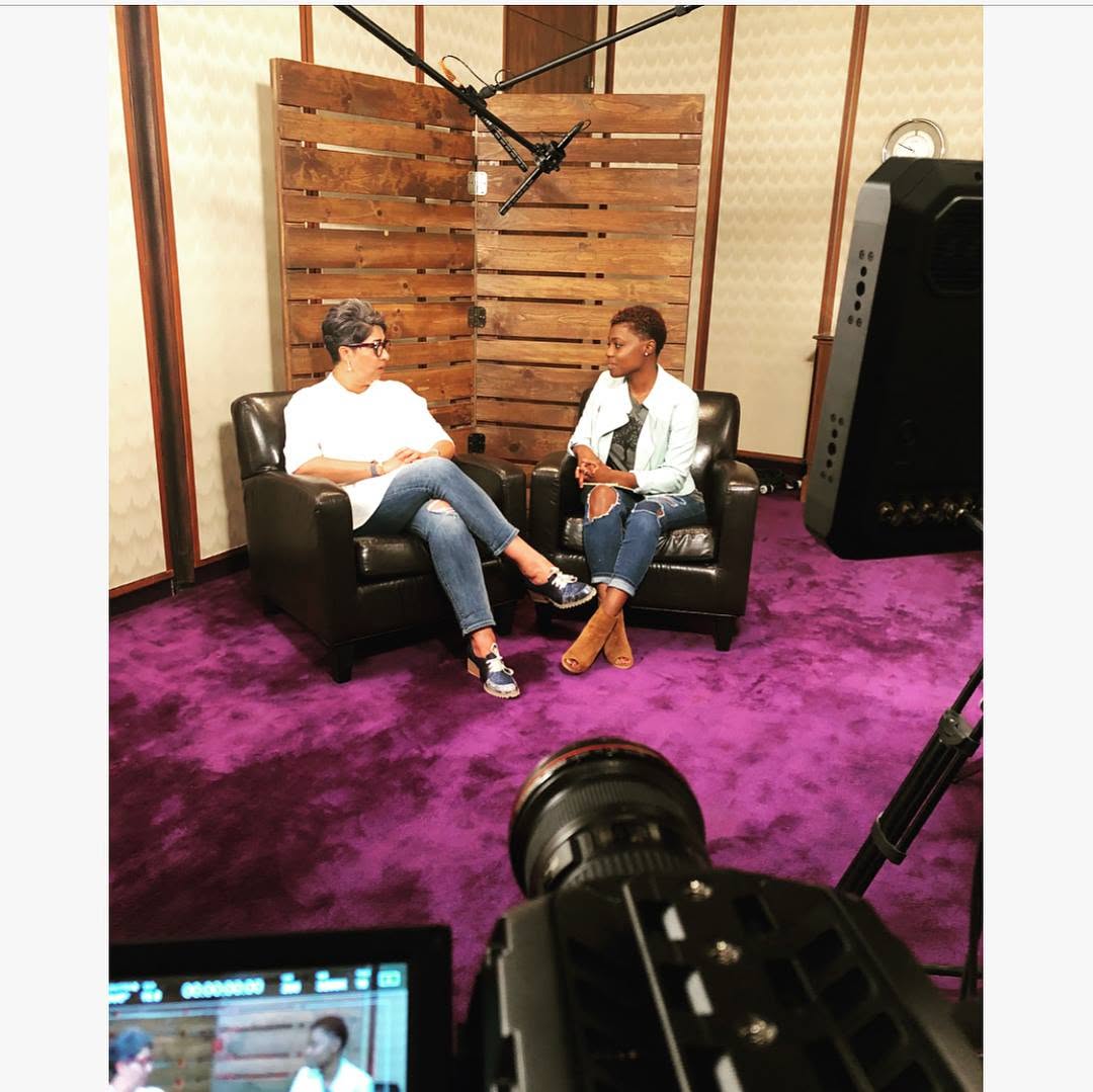 Talk-show style interview being filmed on a studio set with boom mic and camera