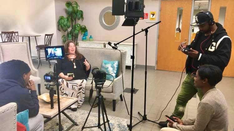 On-set interview production with host, cameras, lighting, and crew